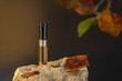 Beautiful glass sprayer bottle standing on a stone with apple leaves. Autumn cosmetic concept composition. Wooden scent perfume sample presentation. Luxury product advertising concept or mockup