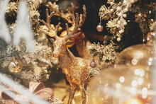 Stylish Golden Reindeer And Modern Christmas Tree With Glitter Baubles In Window, Fairytale Decoration. Atmospheric Magic Time. Christmas Festive Decor For Winter Holidays. Merry Christmas!