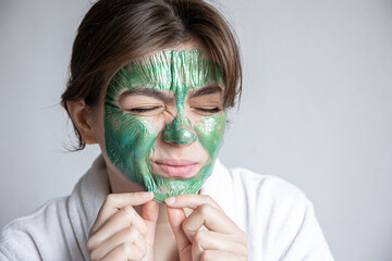 Wall Mural - Removing a green cosmetic mask from the attractive girl face.