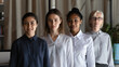 © fizkes - Female business team. Portrait of four experienced multiethnic women of older younger generation looking at camera at office area. Elderly lady teacher and international group of students stand in row