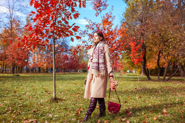 Wall Mural - Full body portrait of beautiful woman wearing stylish clothes, boots, accessories in autumn park. Female fall fashion