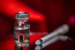 © Gevorg Simonyan - A medical vial with a vaccine containing a microchip inside, the image on a red background. An image with a shallow depth of field.