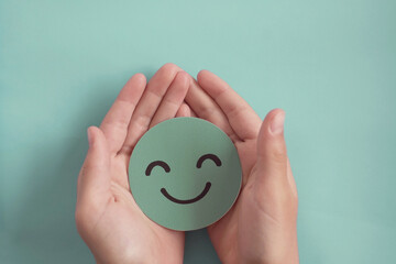 Hands holding green happy smile face, good feedback rating,positive customer review, experience, satisfaction survey ,assessment, child wellness,world mental health day, Compliment Day concept