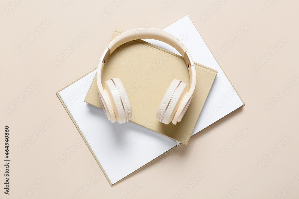 Modern headphones and books on color background