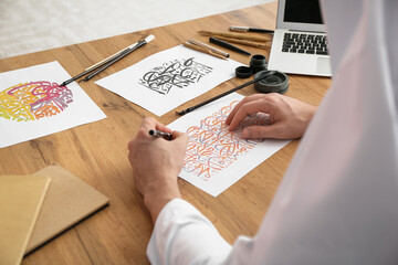 Male Arab calligraphist working in office