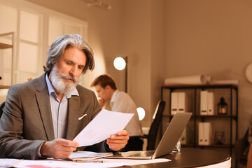 Wall Mural - Mature businessman working with documents in office at night