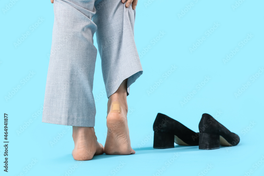 Legs of young woman with adhesive patch on blue background