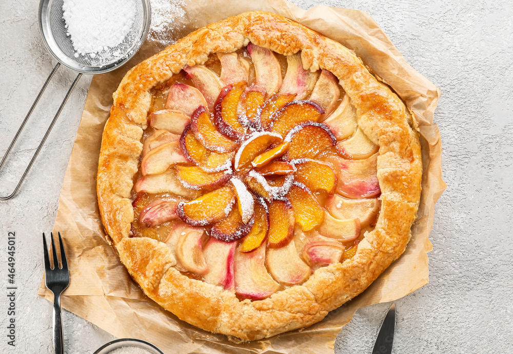 Parchment with tasty peach galette on light background