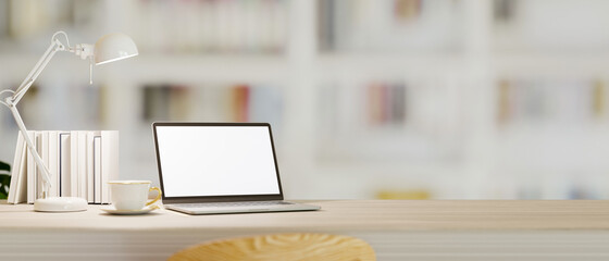 Work table with laptop mockup, decor and empty space over blurred library in background.