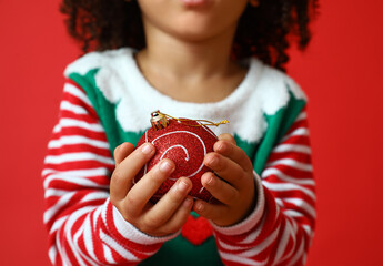 Sticker - Little African-American girl with Christmas ball on red background, closeup