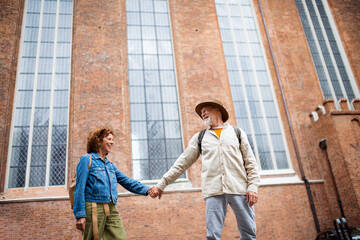 Low angle view of happy senior couple in love holding hands outdoors in town