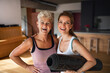© Halfpoint - Active senior woman after workout training with adult daughter indoors at home, looking at camera.