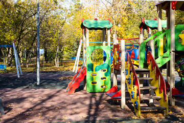 Wall Mural - colorful wooden slides and houses on playground in public city park on sunny autumn day