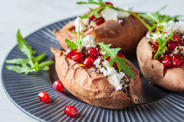 Wall Mural - Whole baked sweet potato stuffed with quinoa, feta cheese, arugula and pomegranate on gray plate. Vegan food concept.