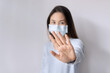 © Pattarisara - Stress young Asian woman wearing medical mask gesturing stop or say no on white background. Copy space, closeup