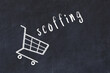 Chalk drawing of shopping cart and word scoffing on black chalboard. Concept of globalization and mass consuming