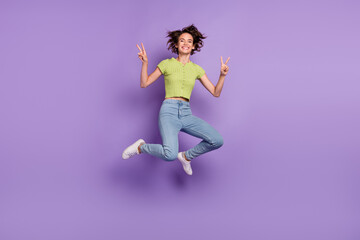 Photo of beautiful pretty young lady wear green t-shirt smiling jumping high showing v-signs isolated violet color background