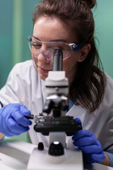 Wall Mural - portrait of microbiologist researcher woman analyzing gmo leaf sample under medical microscope searc