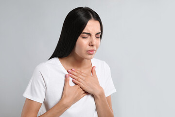 Poster - Young woman suffering from breathing problem on light background