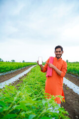 Wall Mural - Young indian farmer showing smartphone screen at agriculture field.