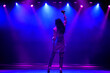 Cool singer with microphone on bright backlit stage in bright blue lights