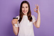© Tetiana - Photo of young girl enjoy cup of coffee show oakey perfect choose sign isolated over violet color background