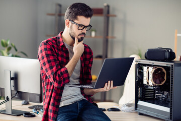 Portrait of attractive minded guy checking server error solving web network problem indoor at work place station