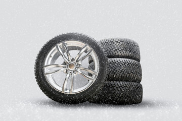 Wall Mural - winter studded tires, a set of friction winter wheels with aluminum alloy wheels on a white background. falling snow is a safety concept about seasonal tire change for safety on the road in icy