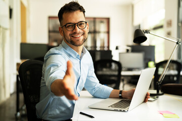 Young businessman working with laptop at office. Businessman giving a hand for handshake
