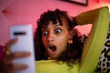Multiracial Young Adult Female Looking Shocked At A Smartphone