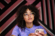 © ReeldealHD images - Young adult female looking up thinking whilst holding a smartphone