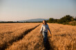 © oksix - Charming woman enjoying moment, walking in grain field