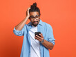 Shocked surprised young african american man looking at smartphone with stunned face expression