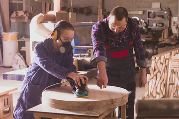 Experienced carpenter teaching young apprentice at workshop