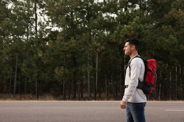 Canvas Print - Man with backpack on road near forest