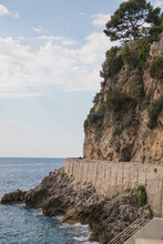 Vertical Shot Of Coastline Cliffs With Bushes Under A Blue Clear Sky In Monaco