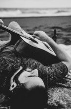 Man Lying On Beach And Playing Guitar In Daytime