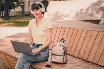 Wall Mural - Photo of young happy nice woman listen music hold laptop sit bench smile outside outdoors city town