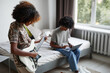 © Seventyfour - Portrait of two teenagers at home, focus on young African-American woman playing electric guitar