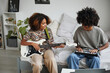 Portrait of two African-American teenagers playing electric guitars at home and smiling happily, brother and sister concept, copy space