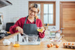 © vacancylizm - Beautiful young woman  is mixing batter, looking at camera and smiling while baking in kitchen at home ,decorating a cake of chocolate cake,cooking class, culinary, bakery, food and people concept