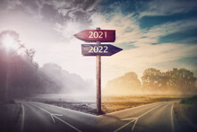 Conceptual Scene Choose Road 2022 Year Or 2021. Split Ways And Signpost Arrows Showing Two Different Courses, Left And Right Go Ahead To The Future Or Turn Back To Past. Life Decision And Choice