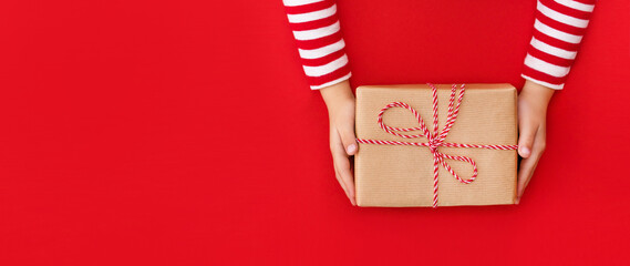 banner gift box in children's hands on a red background, presenting a gift	
