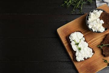 Bread with cottage cheese and microgreens on black wooden table, flat lay. Space for text