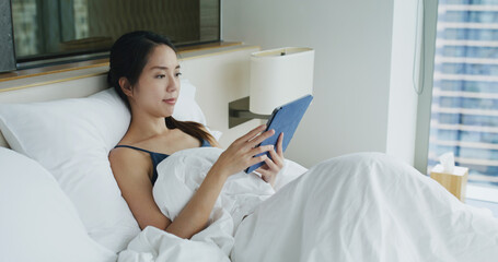 Wall Mural - Woman look at tablet computer and lying on bed