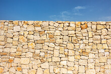 Old Brown Masonry Wall Of Stones And Blue Sky Background. Low Angle View