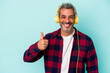 © Asier - Middle age caucasian man listening to music isolated on blue background  smiling and raising thumb up