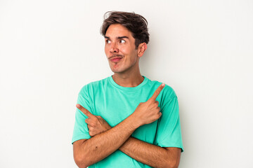 Young mixed race man isolated on white background points sideways, is trying to choose between two options.