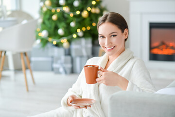 Sticker - Beautiful young woman with cup of hot cacao drink at home on Christmas eve