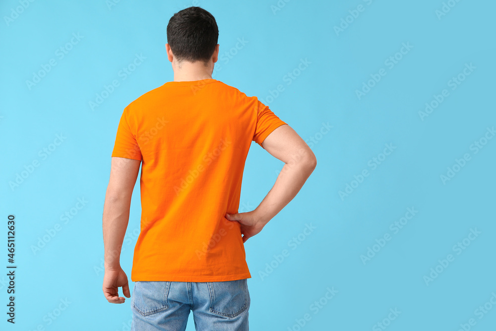 Handsome young man in stylish t-shirt on color background, back view